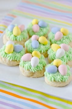 small cookies decorated with green icing and colorful candies on a white platter