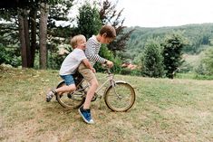 two young boys are riding on a bicycle