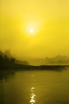 the sun shines brightly over water as it reflects in the fog