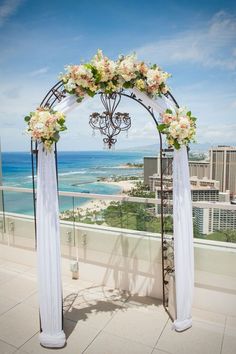 a wedding arch with flowers on it overlooking the ocean