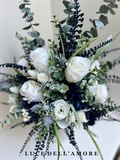 a bouquet of white roses and greenery on a table