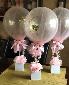 three clear balloons with pink bows and sequins hanging from them on a table