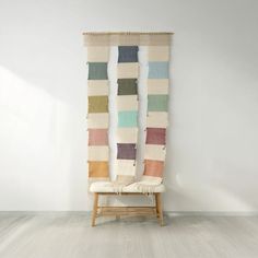 a chair sitting on top of a wooden floor next to a wall covered in multicolored blankets