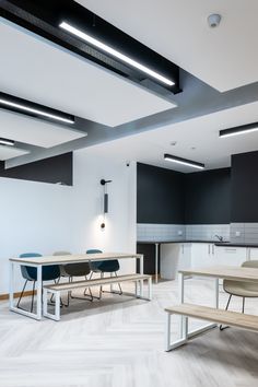 an empty room with tables and benches in the center, lights on overhead above them