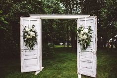 an old door is decorated with flowers and greenery for a wedding ceremony in the woods