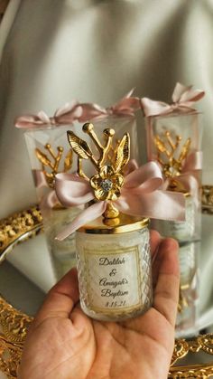 a hand holding a small jar with some gold decorations on it