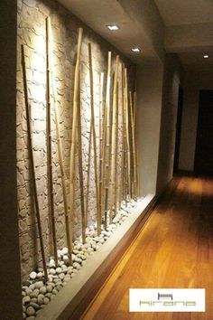 there is a wall with rocks and bamboo sticks on it in the hallway next to a wood floor