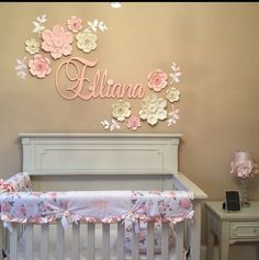 a baby crib with pink and white flowers on the wall