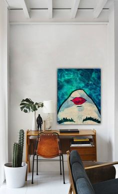 a living room filled with furniture and a painting hanging on the wall over a table