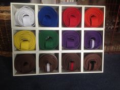 several different colored belts are in a white box on the floor next to a wicker basket