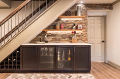 a wine rack under a stair case in a room with wood flooring and stone walls