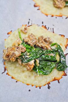 two tortillas with spinach and meat on them are sitting on a baking sheet