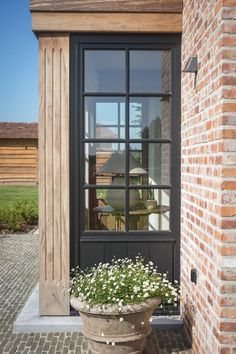 a potted planter with flowers in front of a brick building and glass door