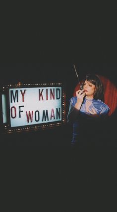 a woman standing in front of a sign that says my kind of woman on it