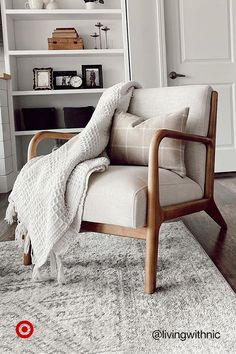 a chair with a blanket on it sitting in front of a book shelf