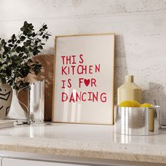 this kitchen is for dancing framed art print on a counter top next to a potted plant