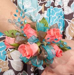 a close up of a person's hand holding a flower arrangement in their left arm