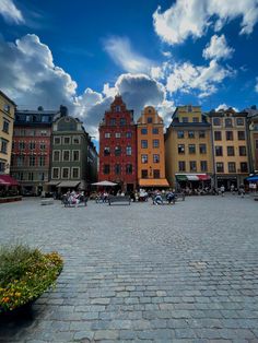 people are walking around in the middle of an open area with many buildings on either side