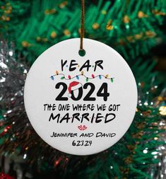 a white ornament hanging from a christmas tree with the year 2024 printed on it