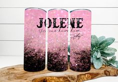 three personalized pink and black flasks sitting on a wooden slab with succulents