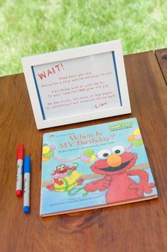 the sesame street book is next to a marker and pen on a wooden table with a sign that says, i want my birthday