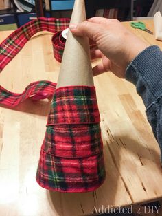 a person is making a cone out of fabric on a wooden table with other items in the background