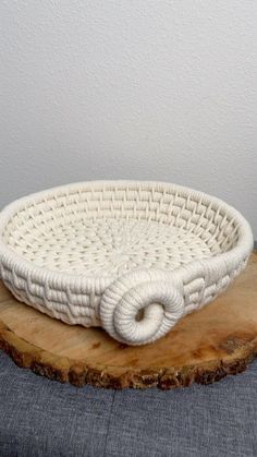 a white woven basket sitting on top of a wooden slab