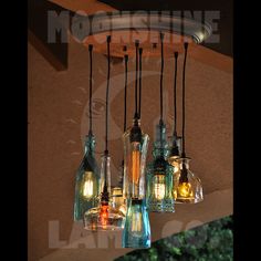 a chandelier made out of glass bottles with lights hanging from the ceiling above it