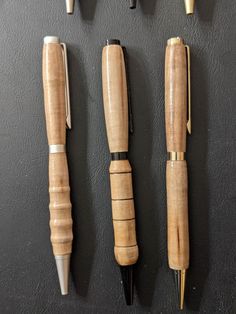 four different types of pens lined up on a black surface with gold trimmings