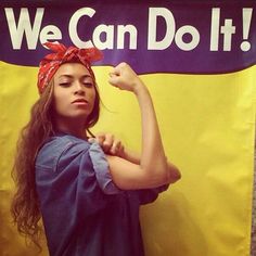 a woman posing in front of a we can do it sign with her arm up