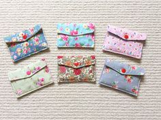 six small wallets are lined up on the floor