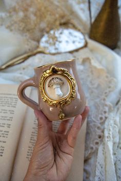 a person holding a coffee cup with a ring on it and an open book in the background