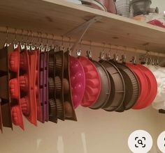 a shelf filled with lots of different colored pots and pans hanging from it's hooks