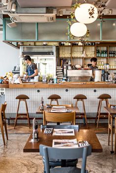 the interior of a restaurant with wooden tables and chairs in front of an open kitchen