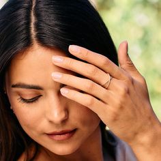 a close up of a person holding their hand to her forehead with both hands and looking down