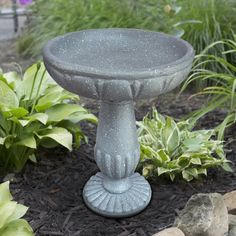 a bird bath sitting on top of a flower bed