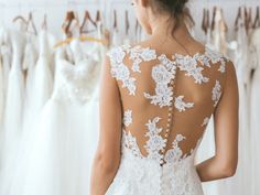 the back of a woman's dress in front of wedding gowns