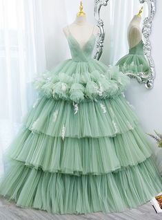 Do you seek to embody the spirit of nature on your prom night? Draped in this gown of gentle green tulle, you'll echo the beauty of a forest at dawn. The bodice, with its plunging neckline, is both daring and delicate, a perfect prelude to the layers of ruffled tulle that cascade into a lush, full skirt. Floral accents are sprinkled across this verdant landscape, lending an air of whimsy and wonder. This dress is a celebration of natural beauty, designed for the dreamer who delights in the dance of leaves and the poetry of petals. Green Sweet 16, Gown Green, Sweet 16 Dress, Dress Quinceanera, Green Tulle, 16 Dress, Long Prom Gowns, Floor Length Skirt, فستان سهرة