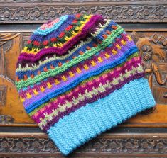 a multicolored knitted hat sitting on top of a wooden bench