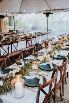 a long table set with plates and place settings for an outdoor wedding reception under a tent