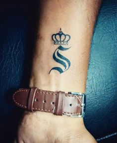 a man's wrist with a crown and snake tattoo on the left side of his arm