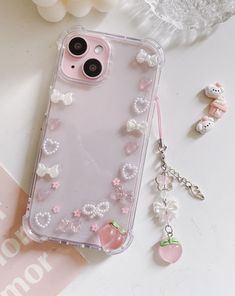 an iphone case with pearls and bows on it next to a keychain, earring