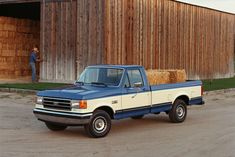 a blue and white pick up truck parked in front of a barn