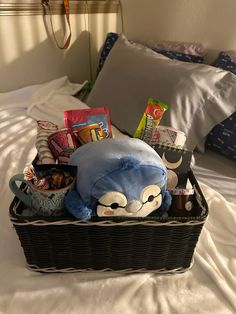 a stuffed animal in a basket on top of a bed with pillows and pillow cases