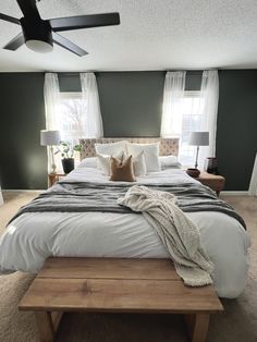 a large bed sitting in the middle of a bedroom next to two lamps and windows