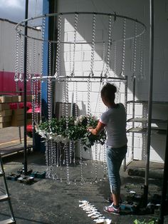 a person standing in front of a tall metal structure with plants growing out of it