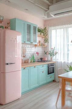 a pink refrigerator freezer sitting inside of a kitchen next to a table and chairs