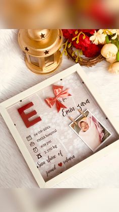 a photo frame with the letter e on it next to flowers and a candle holder