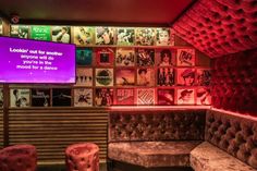 the inside of a bar with red lighting and pictures on the wall behind it,