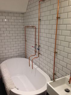 a white bathtub sitting next to a sink in a bathroom with brick walls and flooring